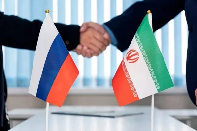 Dois homens apertam as mãos em frente às bandeiras da Rússia e do Irã. (Foto: en.mehrnews.com)