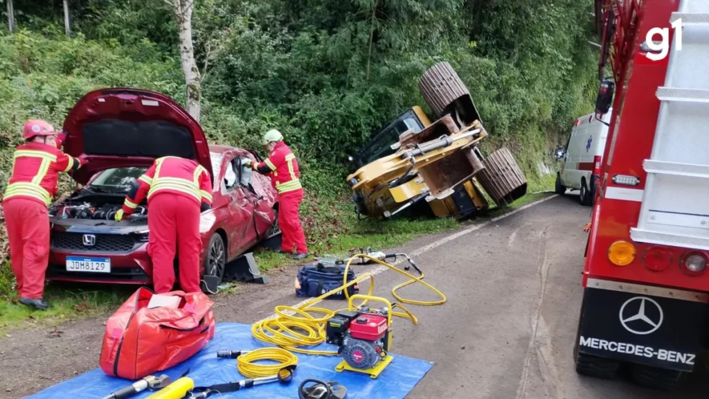 Bombeiros atuam em acidente na BR-116, onde retroescavadeira caiu de caminhão e atingiu carro. (Foto: g1.globo.com)