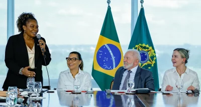 Mulher discursa em reunião com bandeiras do Brasil ao fundo. (Foto: Wikimedia Commons)