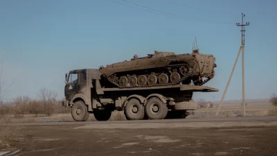 Caminhão transporta um tanque militar em estrada rural. (Foto: rt.com)