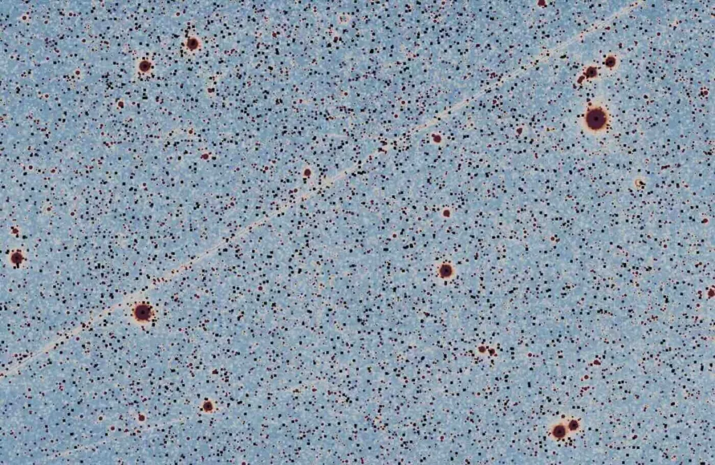 Imagem cósmica captada pelo telescópio SPHEREx, mostrando pontos estelares e trilhas de satélites artificiais. (Foto: thedebr