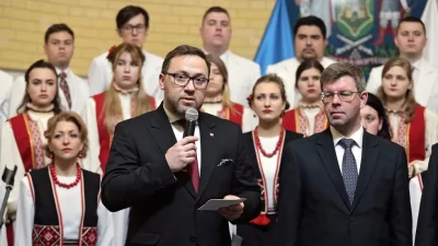 Bartosz Cichocki discursa em evento com coro tradicional ucraniano ao fundo. (Foto: rt.com)