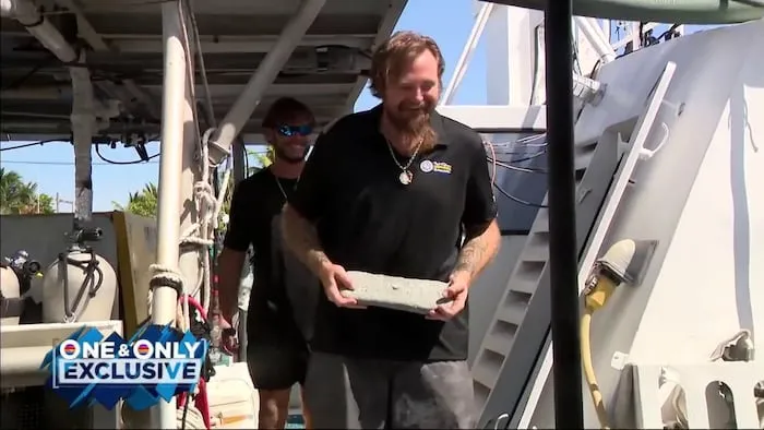 Um membro da equipe de mergulho segura uma barra de prata encontrada em naufrágio no Florida Keys. (Foto: www.local10.com)