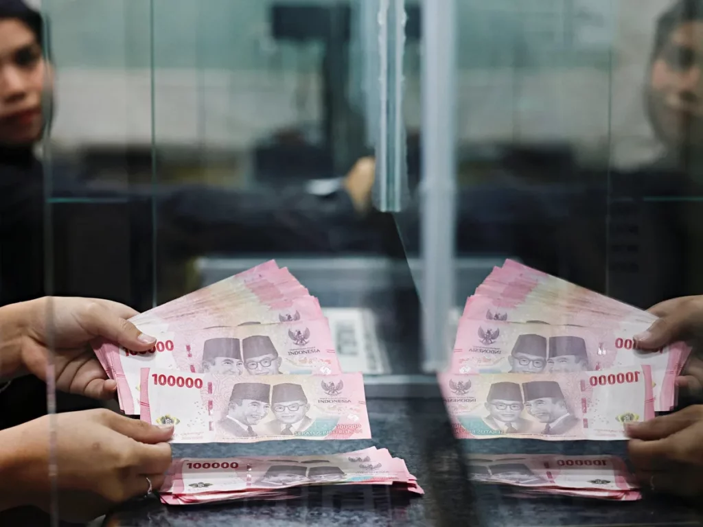 Funcionários contam notas de 100.000 riais indonésios em caixa de banco. (Foto: aljazeera.com)