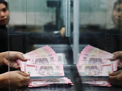Funcionários contam notas de 100.000 riais indonésios em caixa de banco. (Foto: aljazeera.com)
