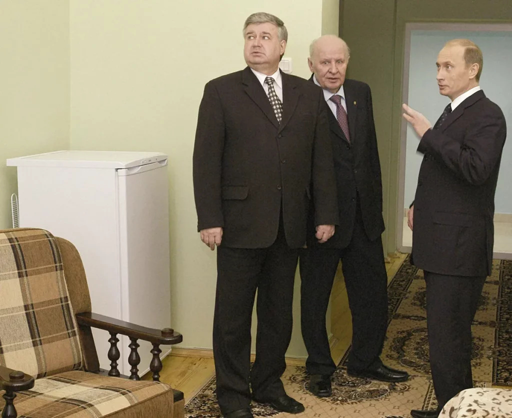 Vladimir Putin em reunião com dois homens em ambiente interno. (Foto: Wikimedia Commons)
