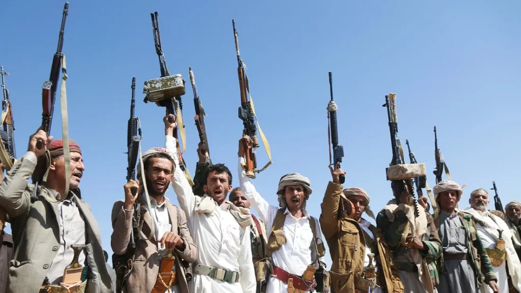 Militantes hutís de Yemen erguem armas em ato de apoio ao governo, sob céu claro. (Foto: actualidad.rt.com)