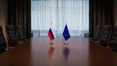 Bandeiras da Rússia e da União Europeia em mesa de reunião, simbolizando diálogo entre as partes. (Foto: actualidad.rt.com)