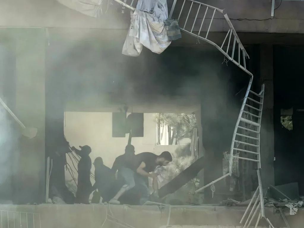 Pessoas em meio aos escombros de um prédio danificado por ataque aéreo em Beirute. (Foto: aljazeera.com)