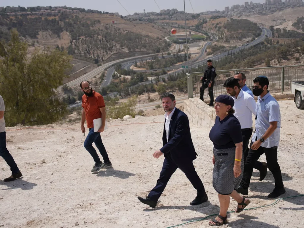 Um grupo de pessoas caminha por área com vista para estradas e colinas em território palestino. (Foto: aljazeera.com)