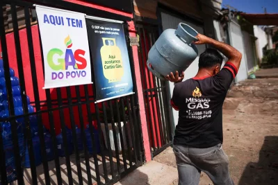 Homem carrega cilindro de gás em frente a loja que vende "Gás do Povo". (Foto: WWW1.FOLHA.UOL.COM.BR)
