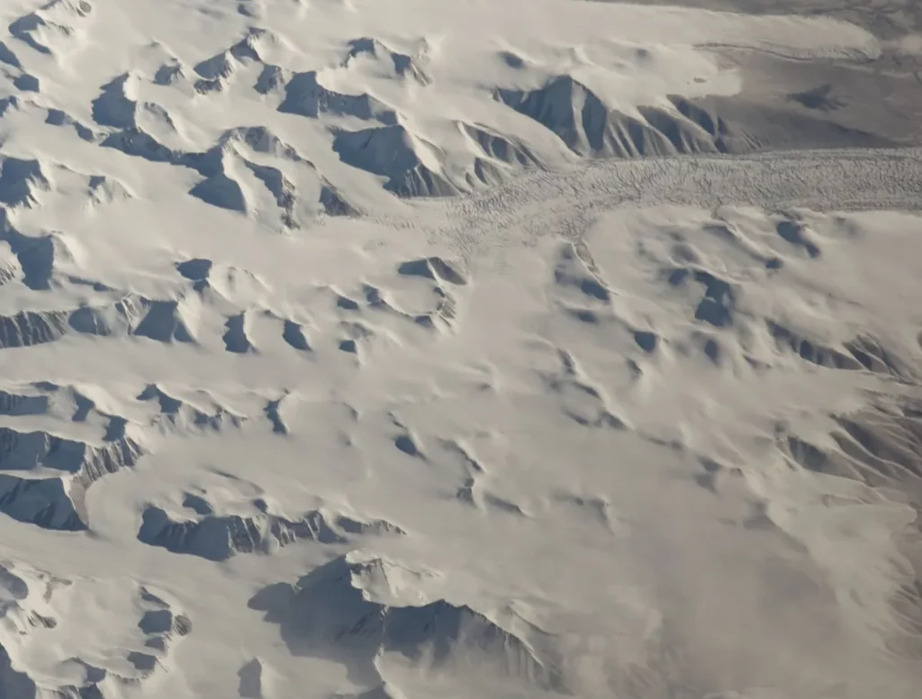 Vista aérea de geleiras cobrindo montanhas nevadas na Antártida. (Foto: Wikimedia Commons)
