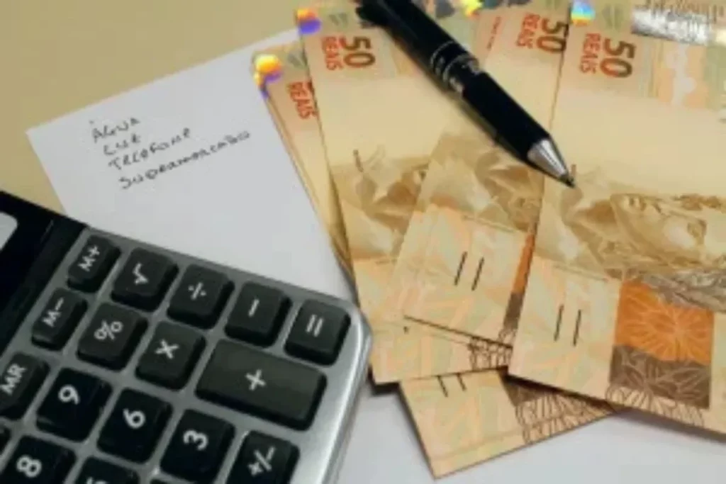 Dinheiro em notas de 50 reais, caneta e calculadora sobre uma lista de contas. (Foto: metropoles.com)