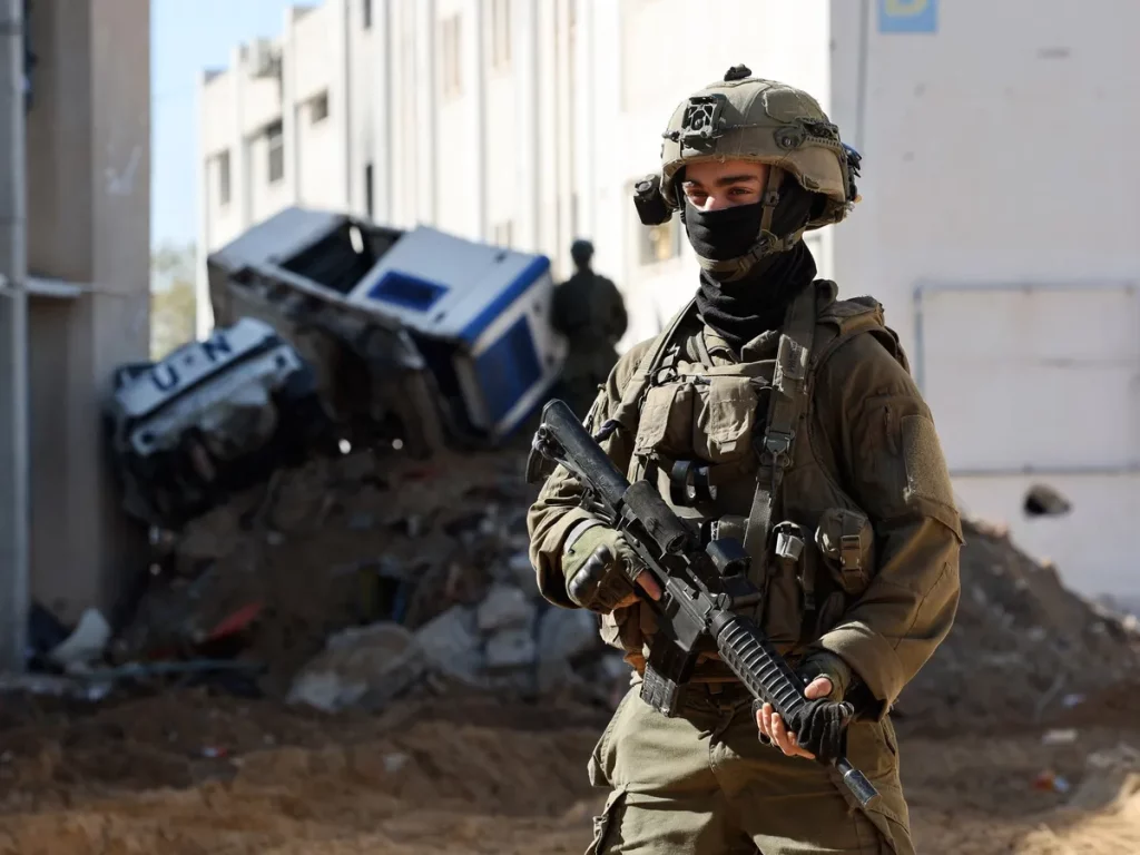 Soldado israelita patrulha área de conflito em Gaza, com veículo da ONU ao fundo. (Foto: aljazeera.com)