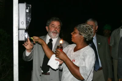 O ex-presidente Lula participa de cerimônia do Programa Luz Para Todos, ao lado de beneficiária com vela acesa. (Foto: operam